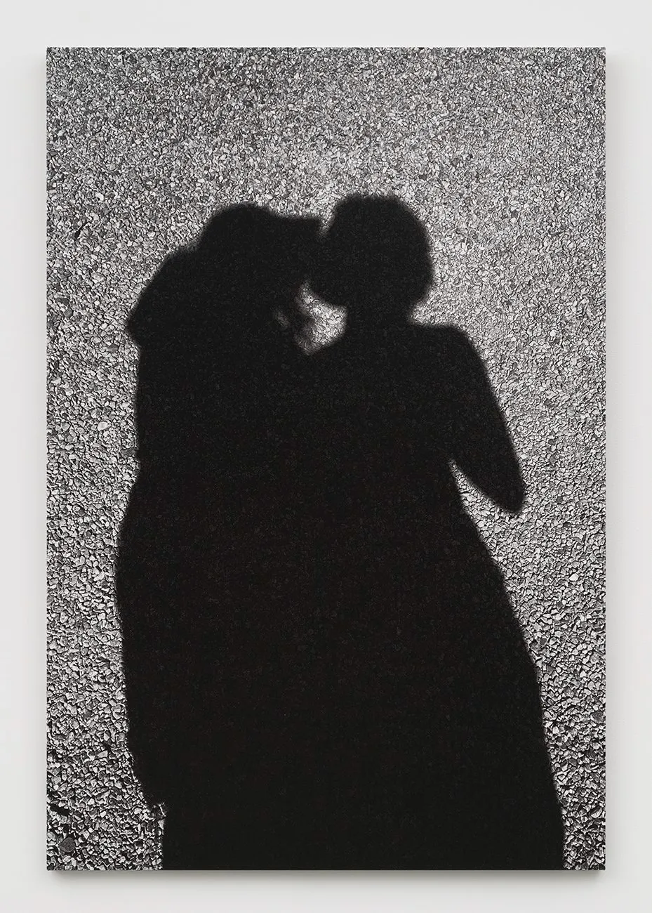 Black silhouette of two people in profile, appearing to kiss, on a textured surface.
