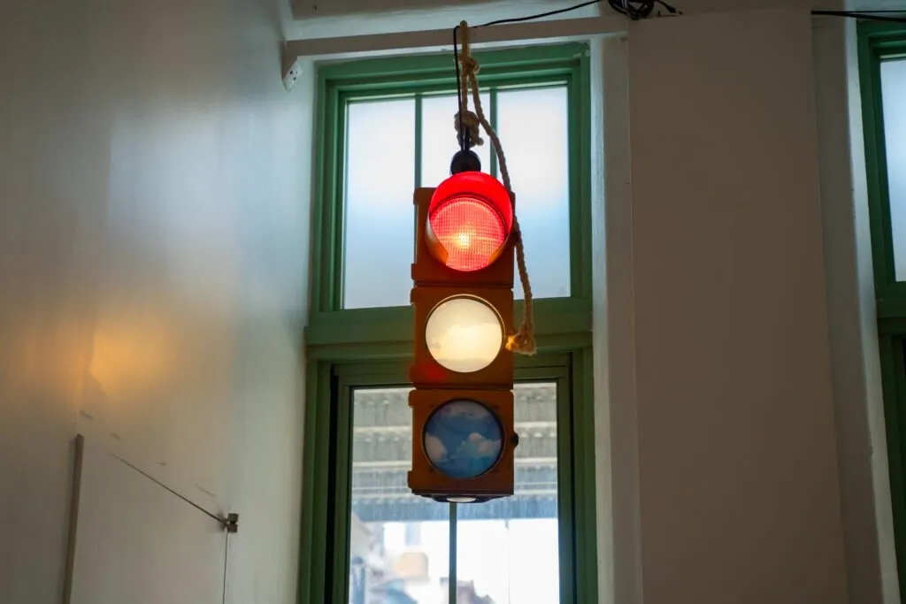 Hanging traffic light with altered signal colors displaying images of clouds instead of solid lights.