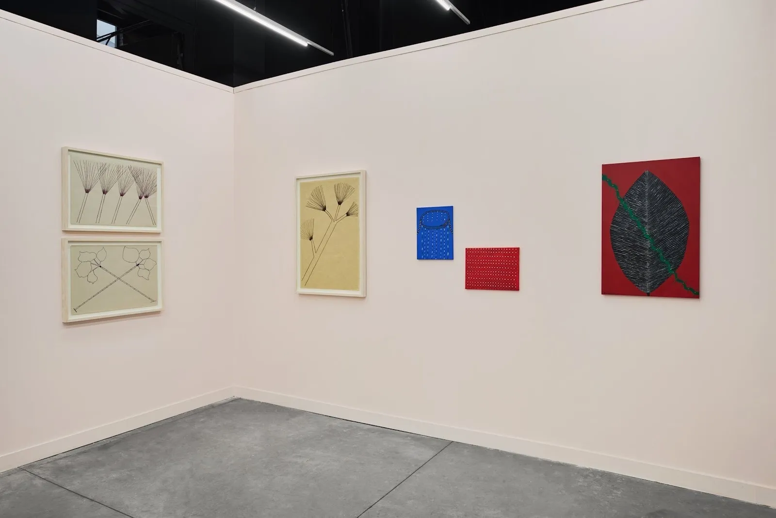 Minimalist booth display of framed botanical drawings and small abstract works arranged along pale pink walls.