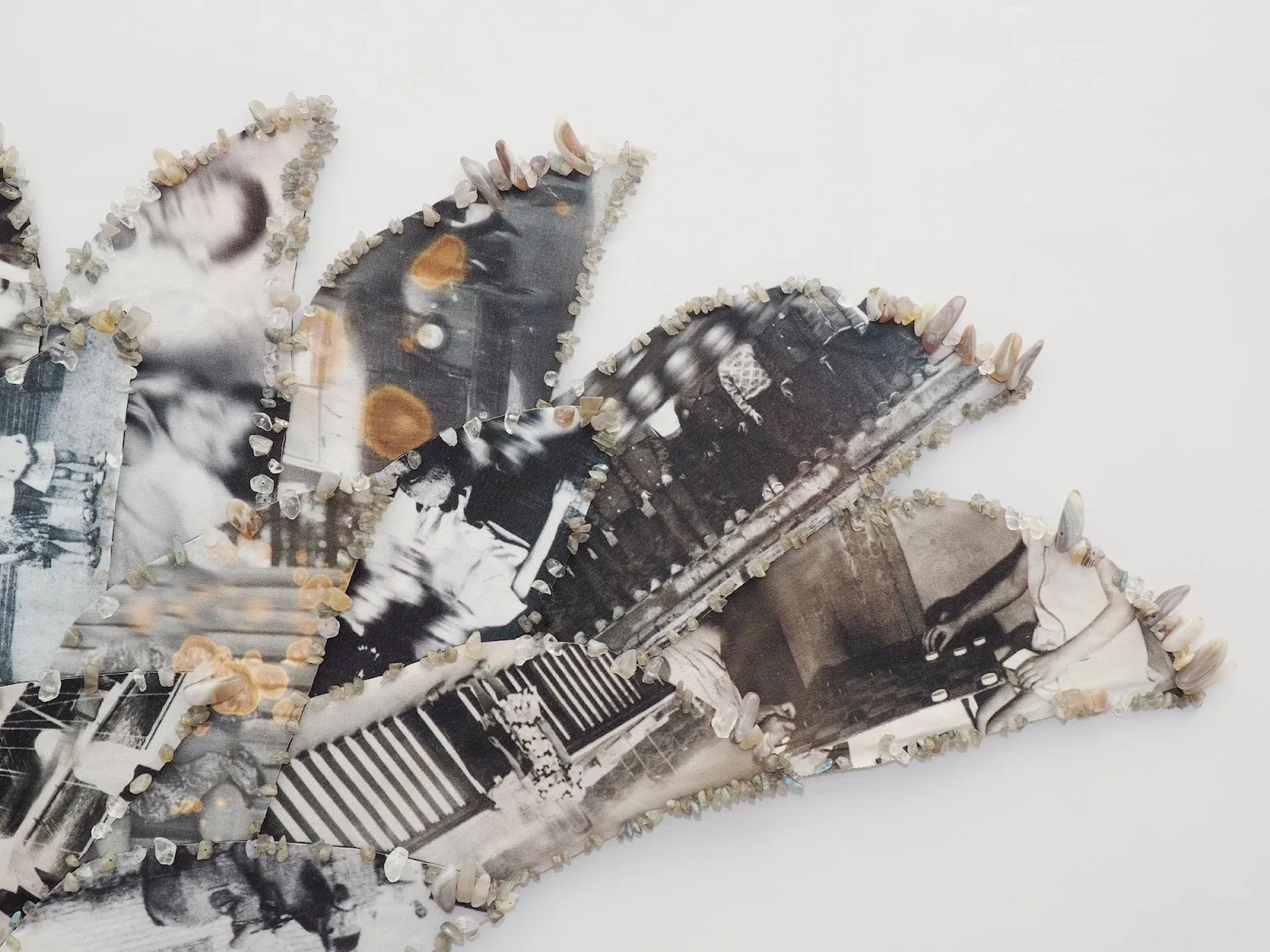 Close-up of a collage-like wall piece edged with small crystals, featuring fragmented black-and-white photographs.