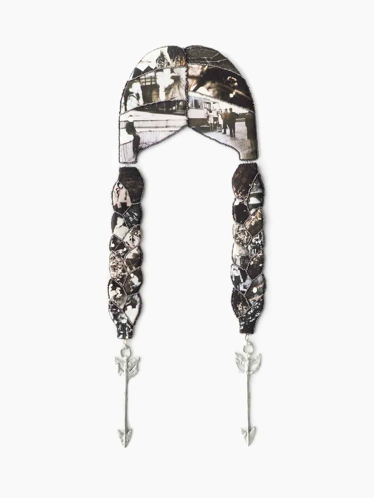 Wall sculpture resembling braided hair, composed of photo fragments bordered with beads and ending in silver arrow charms.