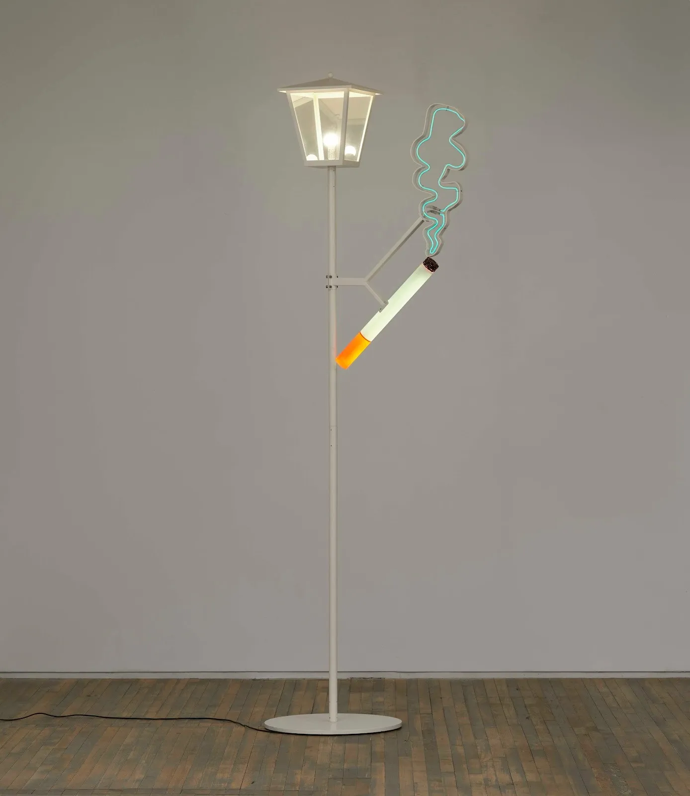 In a white gallery room, a thin, white lamplight stands with a neon cigarette sculpture attached by a branch of adjoining metal.