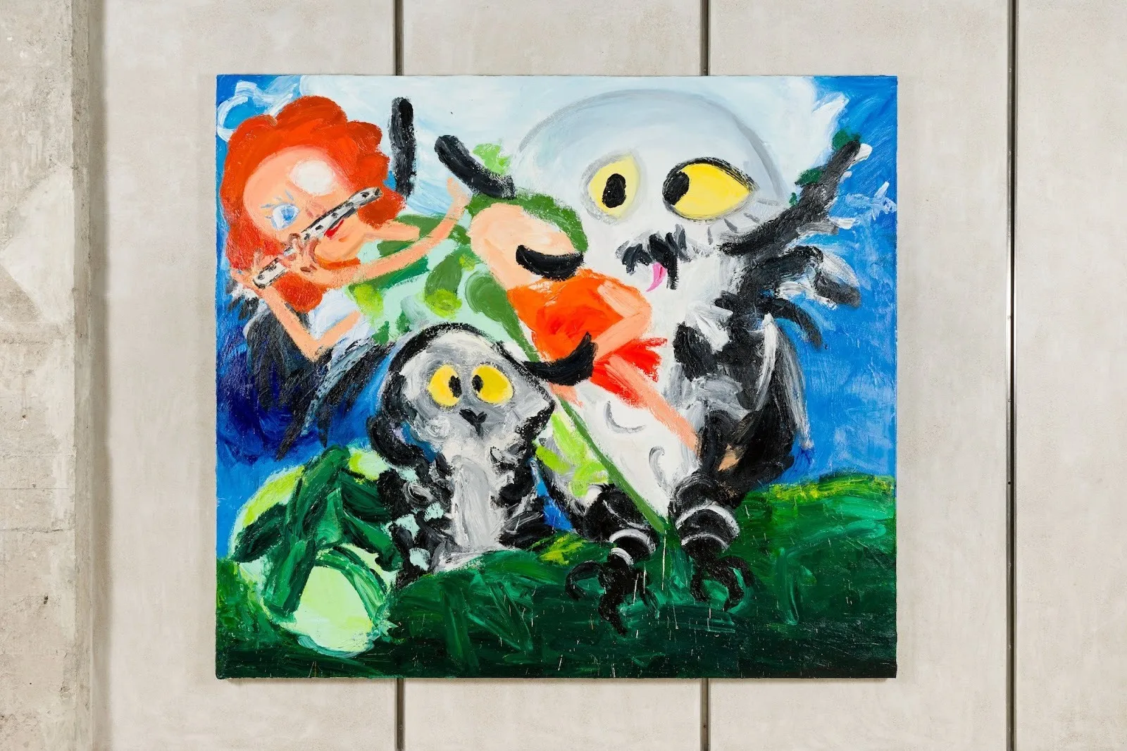 Large painting of a red-haired figure playing a flute while reclining among wide-eyed owls in a vivid, gestural landscape of blue and green.
