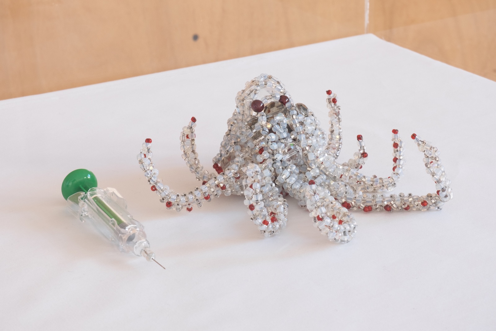Two artworks placed side by side, one is a needle and the other one is a bedazzled octopus-form.