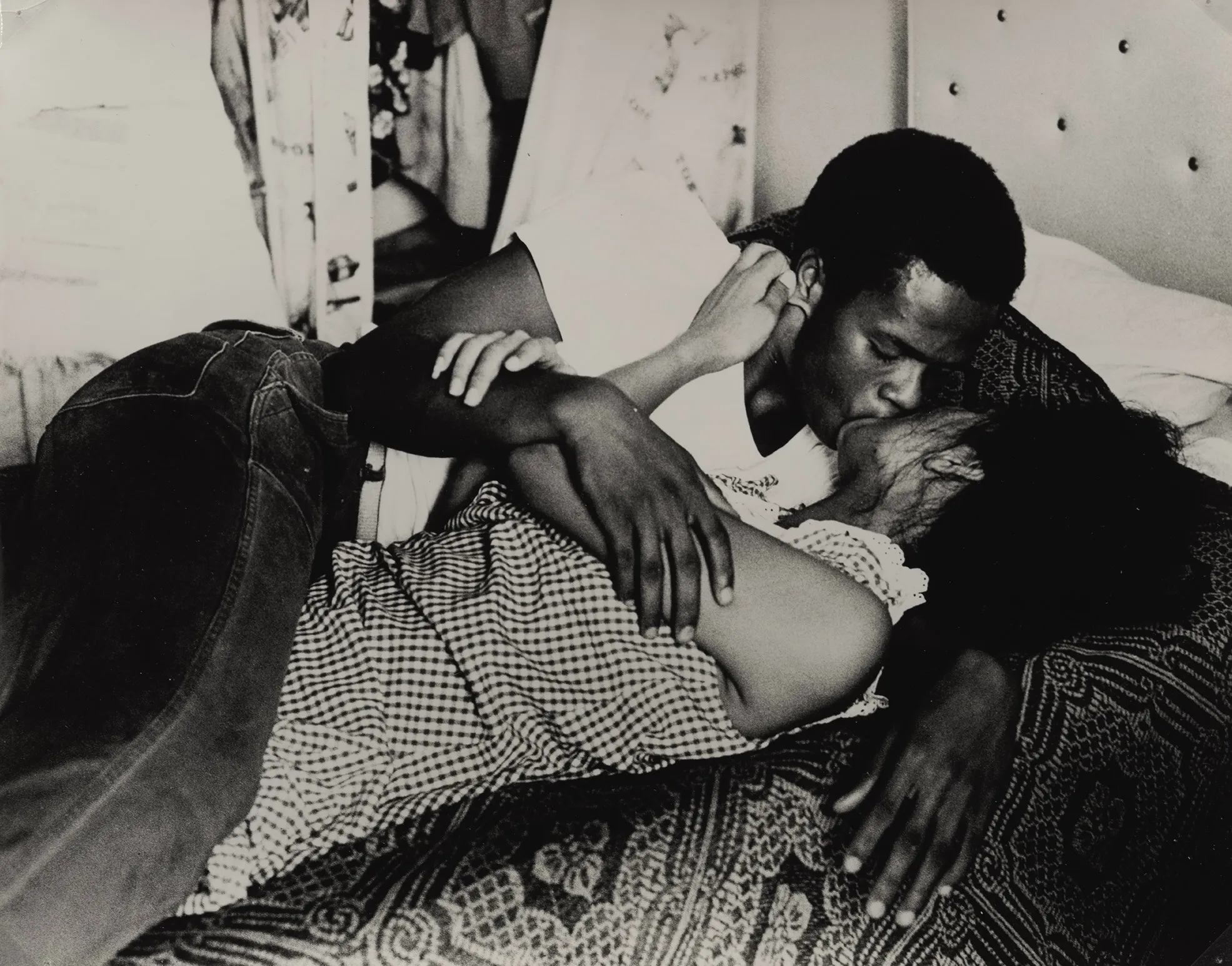 Two people lying on a bed, smiling and embracing, photographed from above at a close, intimate angle.