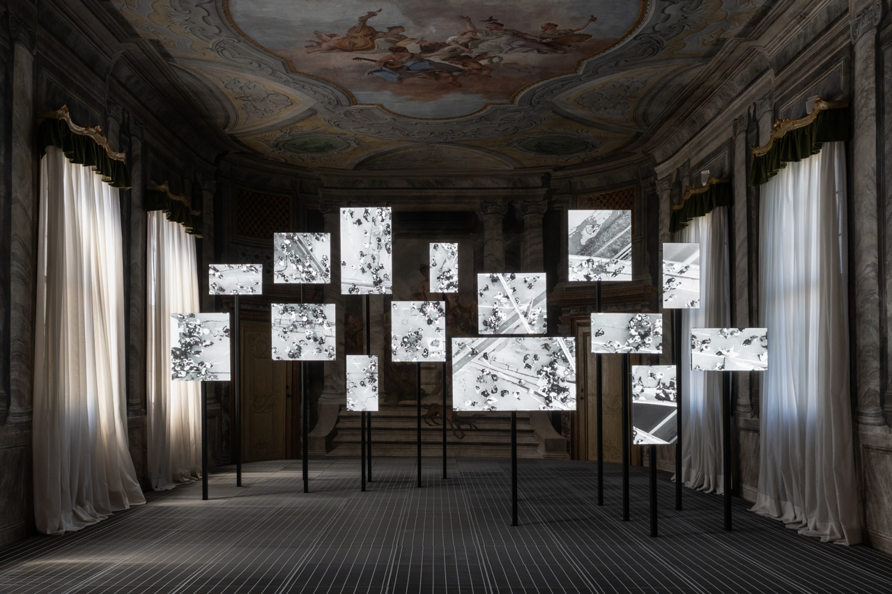 Multi-screen black-and-white video installation in ornate frescoed room.
