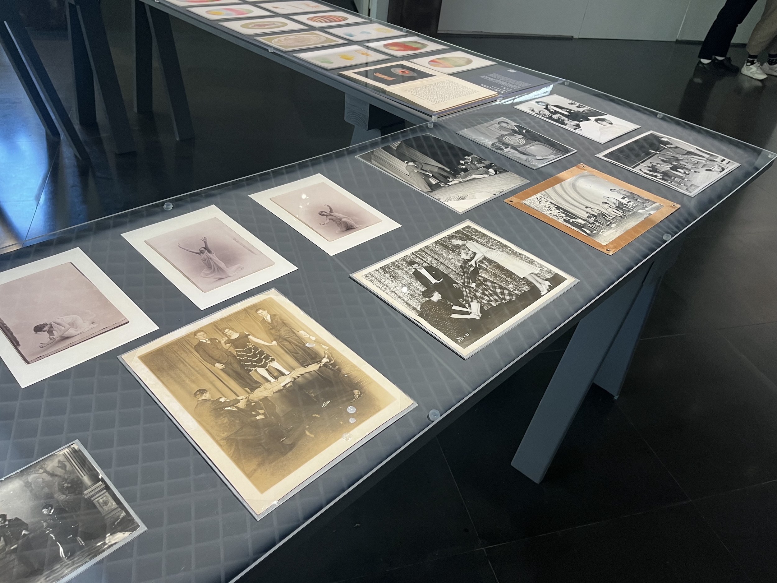 A corner of a table filled with archival photographs, protected by glass.