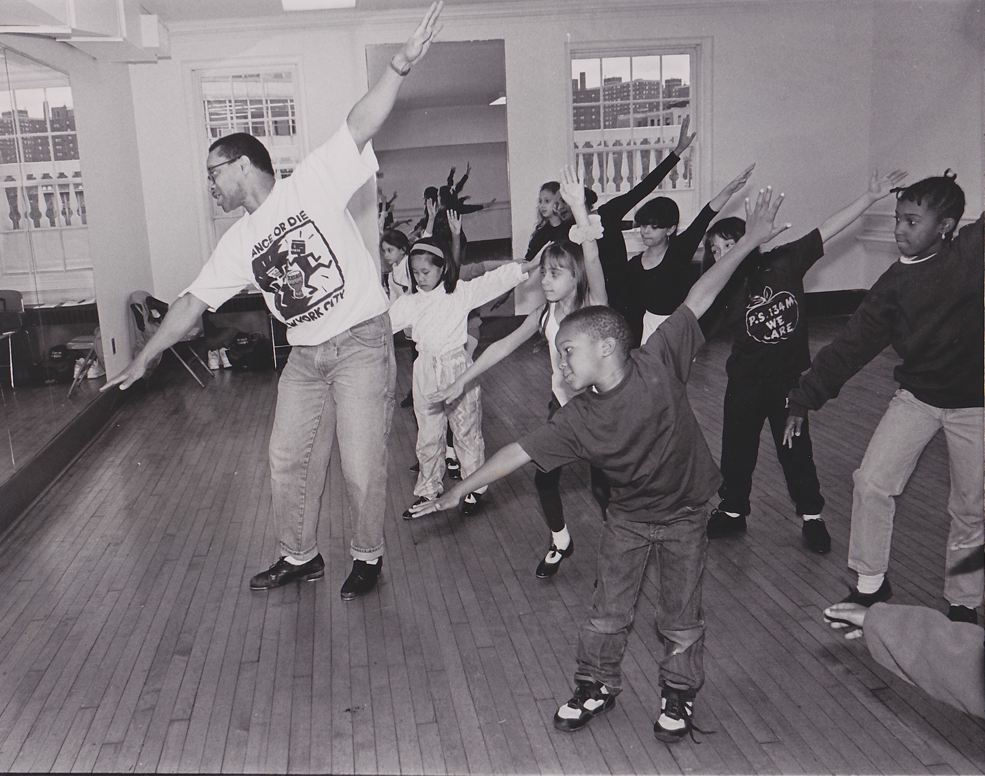 Archival photograph of a dance instructor leading children in a tap dancing studio class.