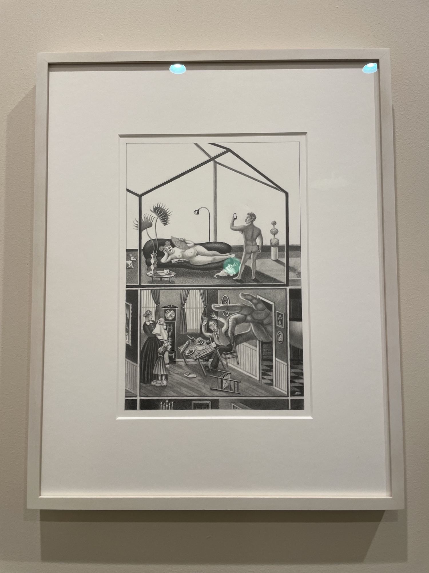 A framed black-and-white pencil drawing in a cross-section "dollhouse" format, showing two stacked interior scenes: an upper room with a reclining nude figure on a chaise and a standing nude man taking a photo with a phone, and a lower Victorian-style dining room where an enormous hand intrudes through a doorway as startled figures react, with a glowing green orb near a cat in the upper room.