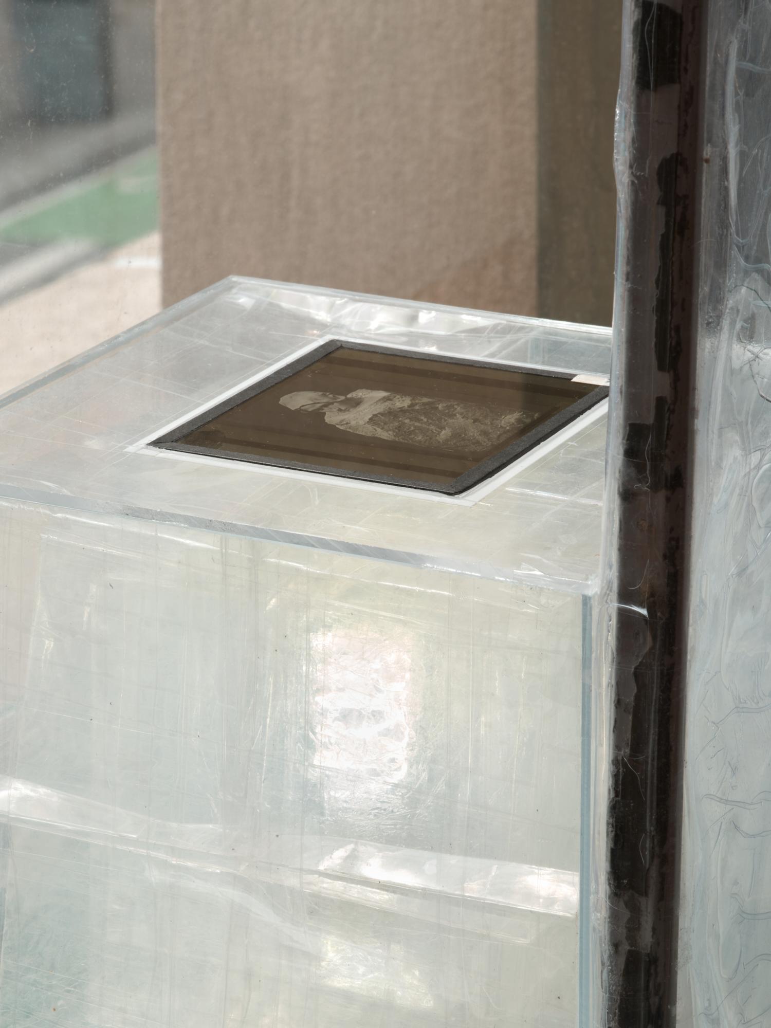 Close-up of a translucent sculptural installation with a small dark photographic image inset on top.