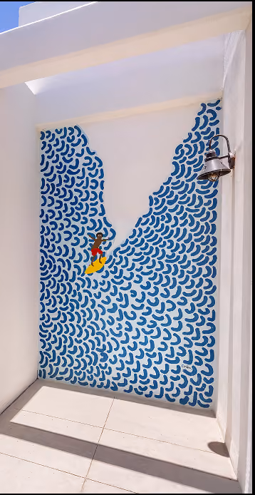 Mural de una persona surfeando una ola formada por pinceladas curvas azules dentro de un pasillo de paredes blancas con una lámpara montada.