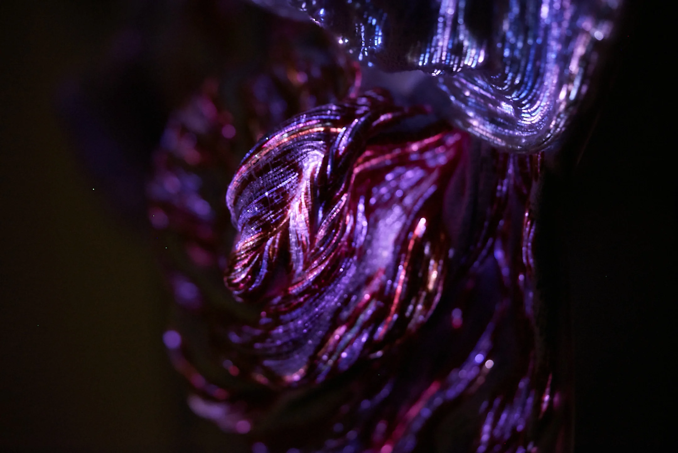 Close-up of a shiny, twisted metallic material with purple and red lighting effects.