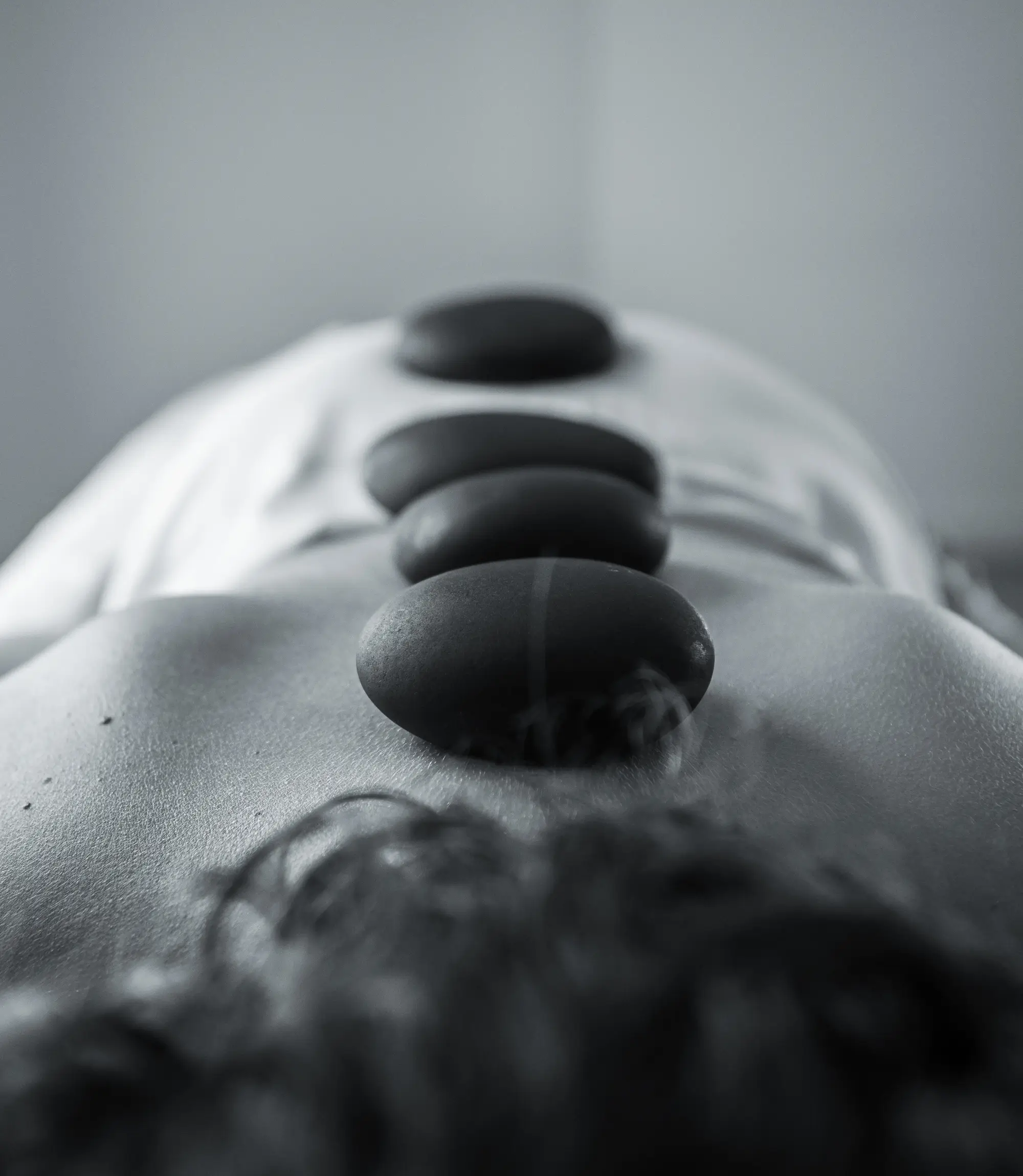 Black massage stones arranged on a person's back during a hot stone therapy session.