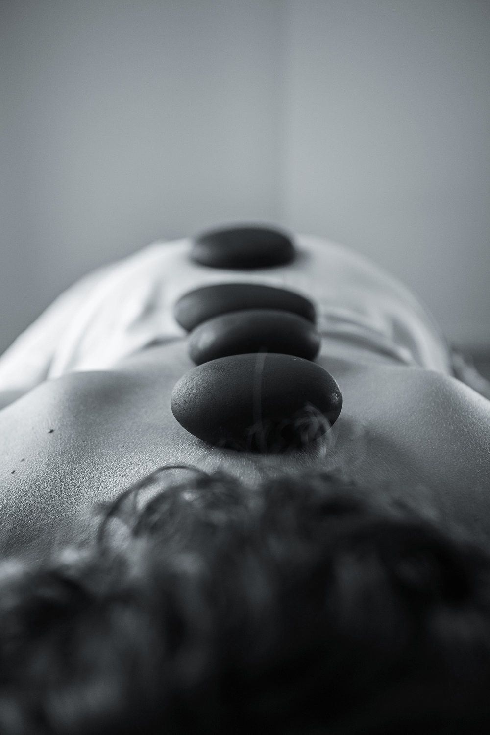 Piedras negras para masaje colocadas sobre la espalda de una persona durante una sesión de terapia con piedras calientes.