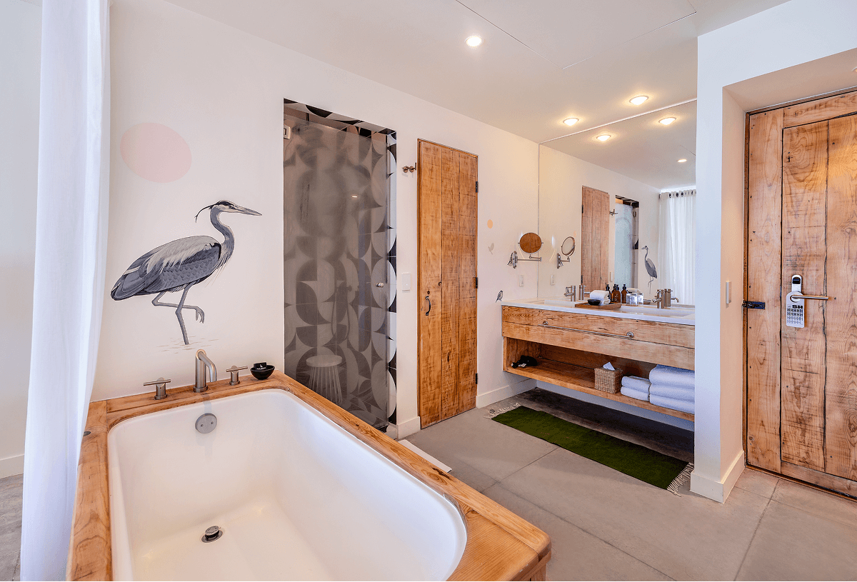 Modern bathroom with wooden accents featuring a rectangular bathtub, a shower with patterned glass door, a double sink vanity with large mirror, and wooden doors.
