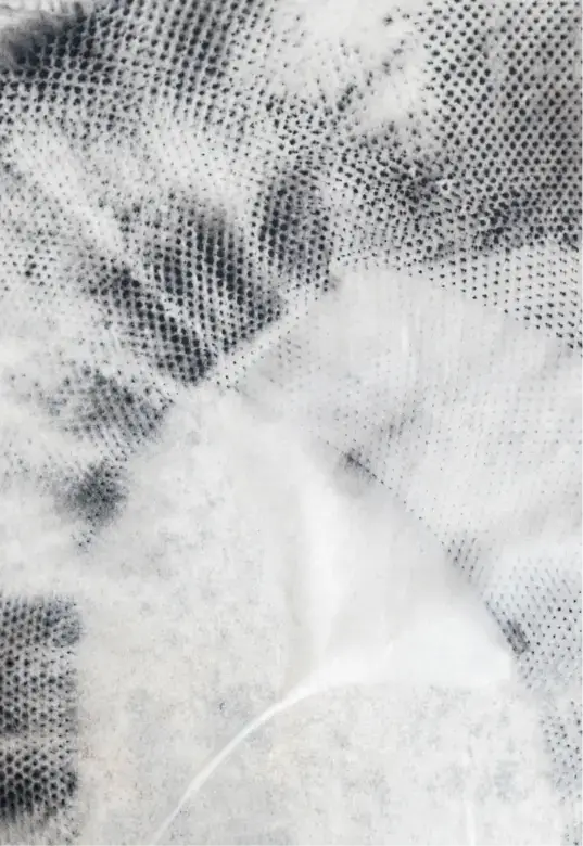 Close-up view of a translucent, textured fabric with a mesh-like pattern in grayscale.