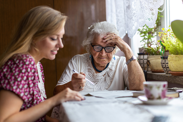 Group of diverse people socializing and eating at a casual indoor gathering near large windows.
