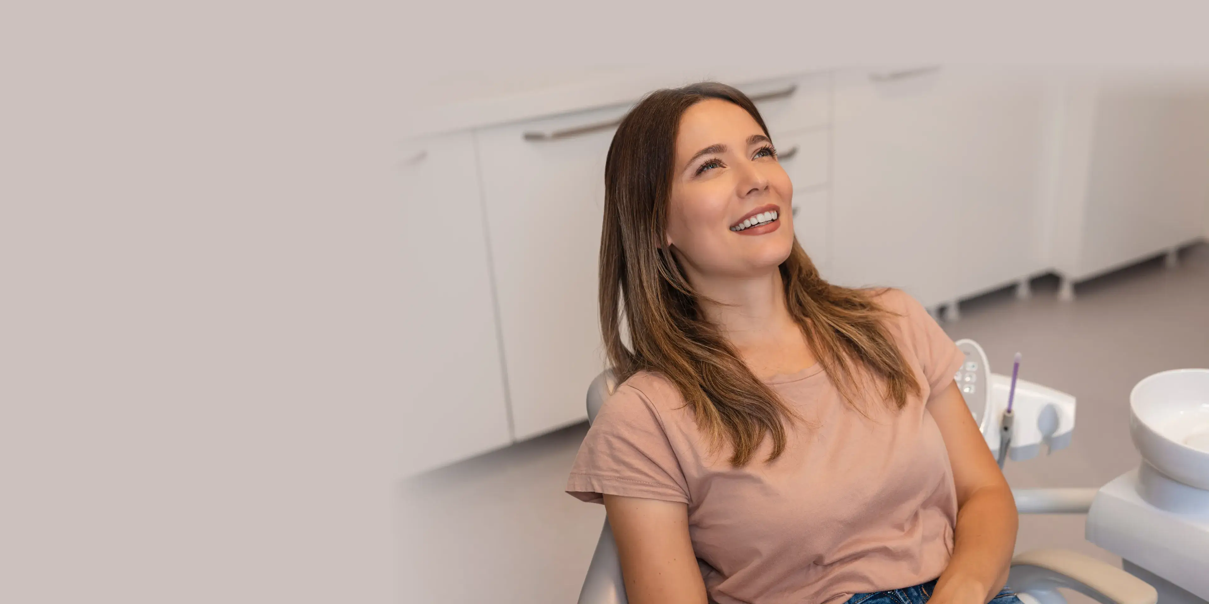 Smiling woman reclining in a dental chair in a modern dental clinic.
