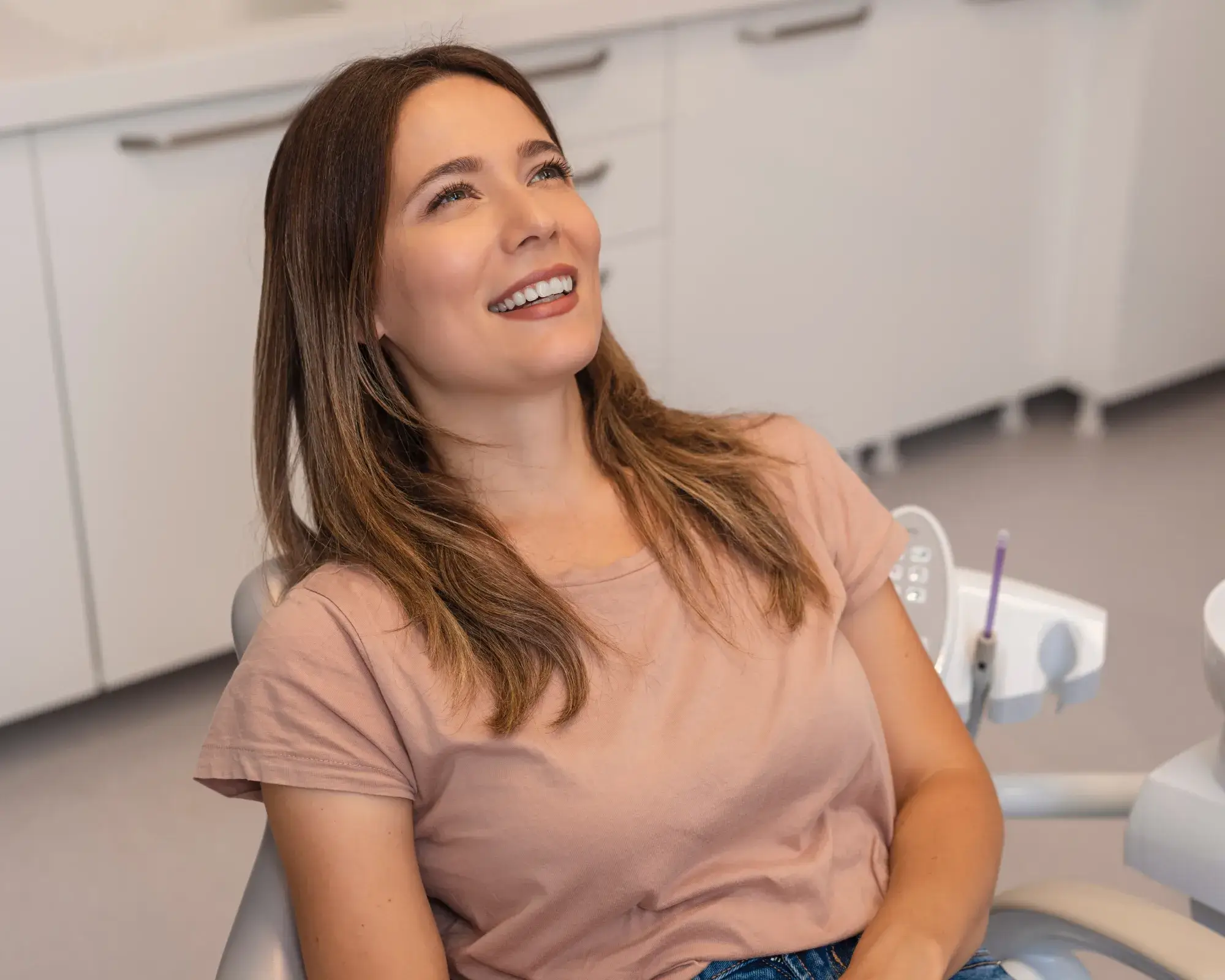 Smiling woman reclining in a dental chair in a modern clinic.