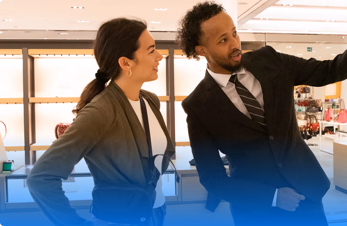 A man in a suit showing a woman shopping in a store, both smiling and engaged.