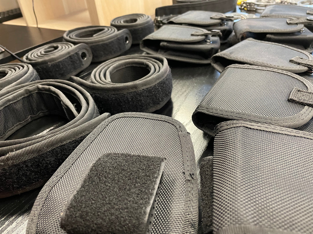 Black nylon straps and pouches with Velcro closures arranged on a dark surface.