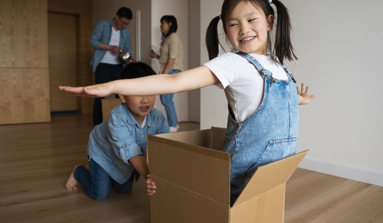 Happy children playing with cardboard boxes while moving with family to new home
