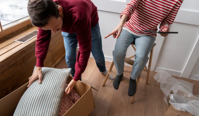 Couple packing pillows in cardboard box together during move preparation