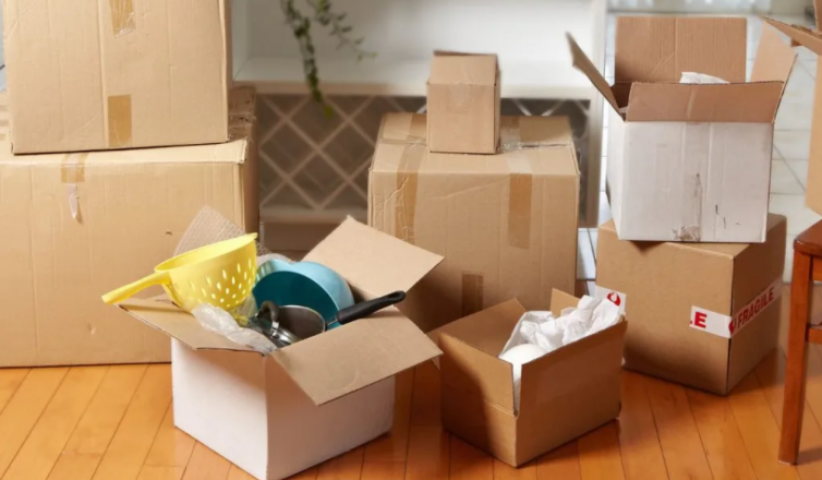 Packed moving boxes with kitchen items to pack first during home relocation