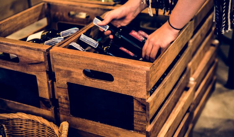Person using wooden crates to pack wine bottles safely for moving
