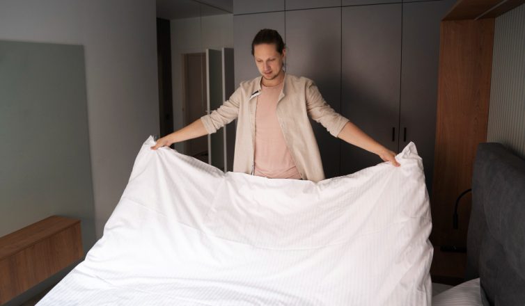 Woman removing bedding from mattress in bedroom during moving preparation