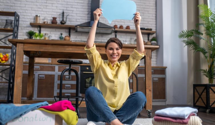 Happy woman celebrating successful moving day surrounded by packed boxes and belongings
