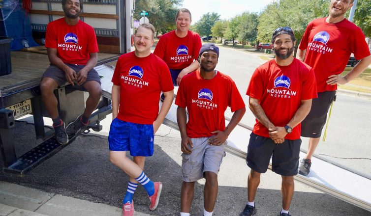 Professional movers team in red uniforms standing by moving truck ready to help