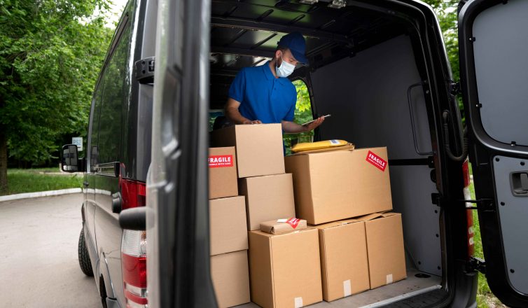 Mover with clipboard checking fragile boxes loaded in moving truck