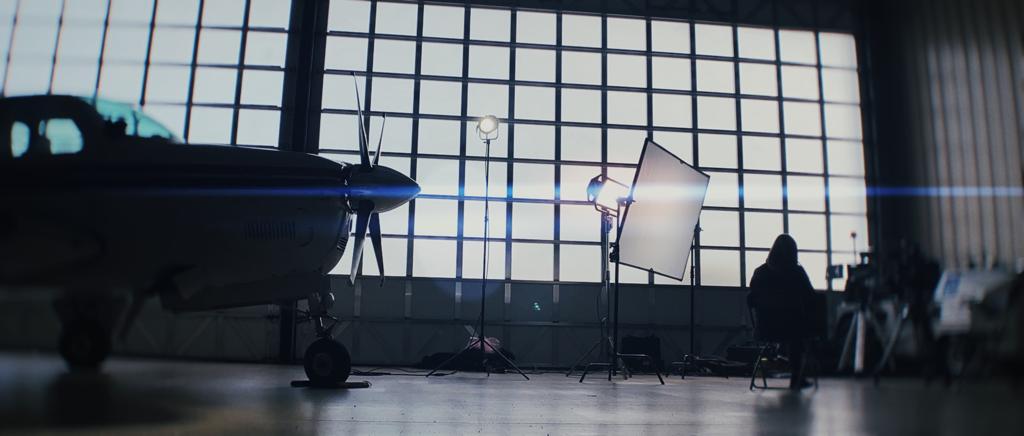 Studio lighting equipment and airplane propeller in a film production hangar with large window grid