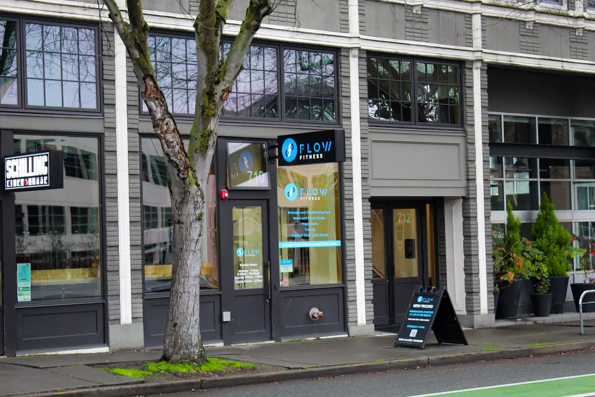 A tree in front of a building with a sign that says Flow Fit.