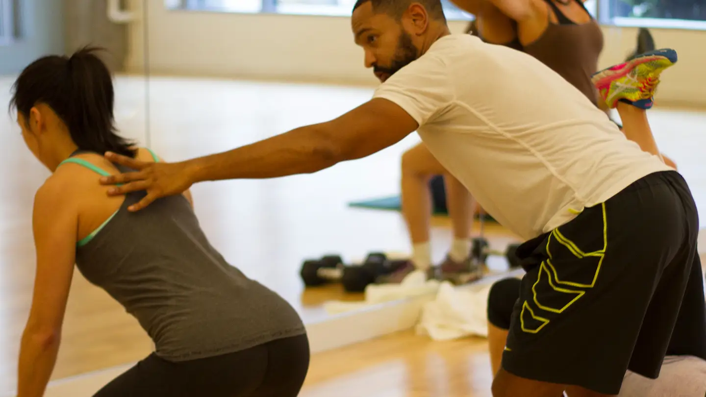 A man is helping a woman with her back exercise.