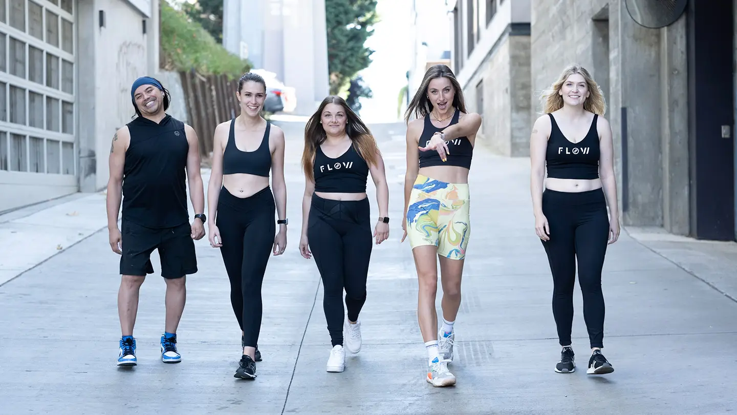 A group of young people wearing black and white athletic clothing are walking down a street.