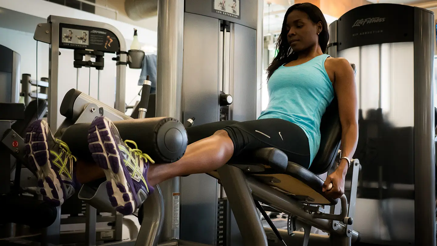 A woman is sitting on a machine in a gym.