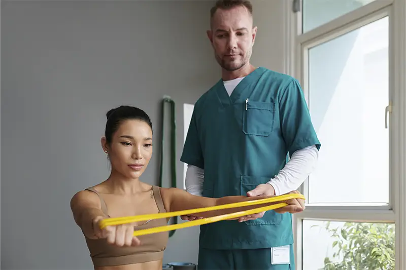 A woman in a brown tank top and a man in a blue shirt and green pants are holding a yellow measuring tape.