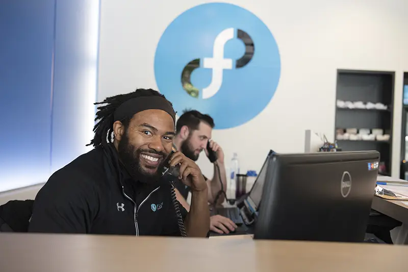 A man smiling while talking on a phone.