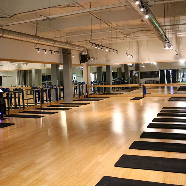 A gym with a wooden floor and black mats.