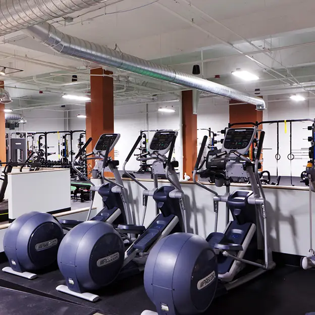 A gym with a row of exercise machines.