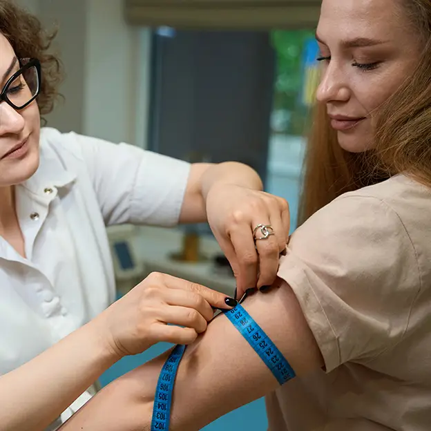 A woman is getting her arm measured by a woman in a white shirt.