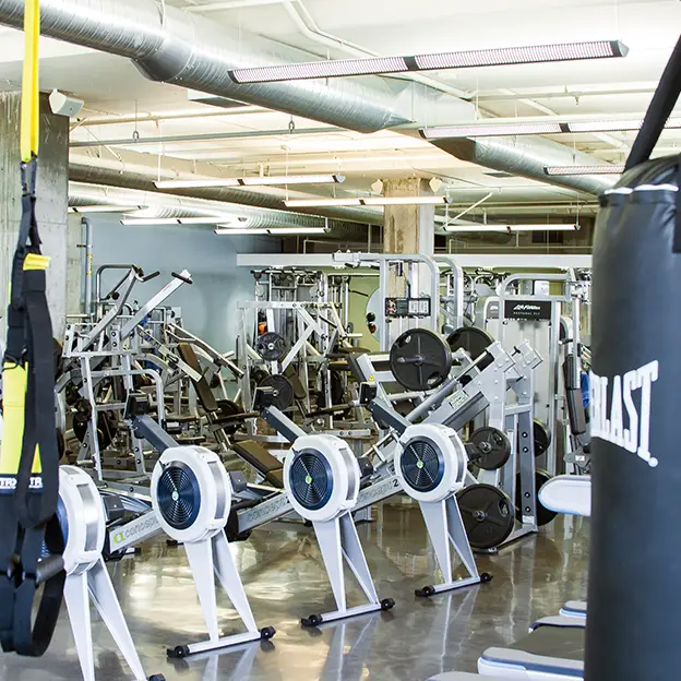 A gym with a yellow boxing bag hanging from the ceiling.