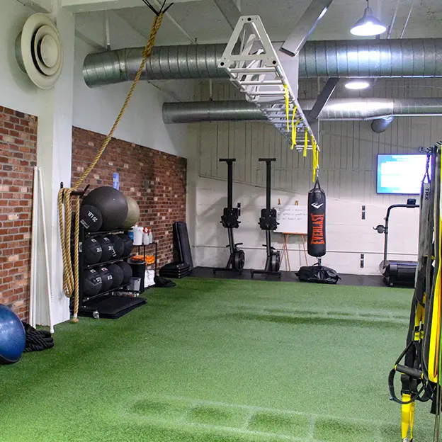 A gym with a green turf floor and a yellow and black machine.