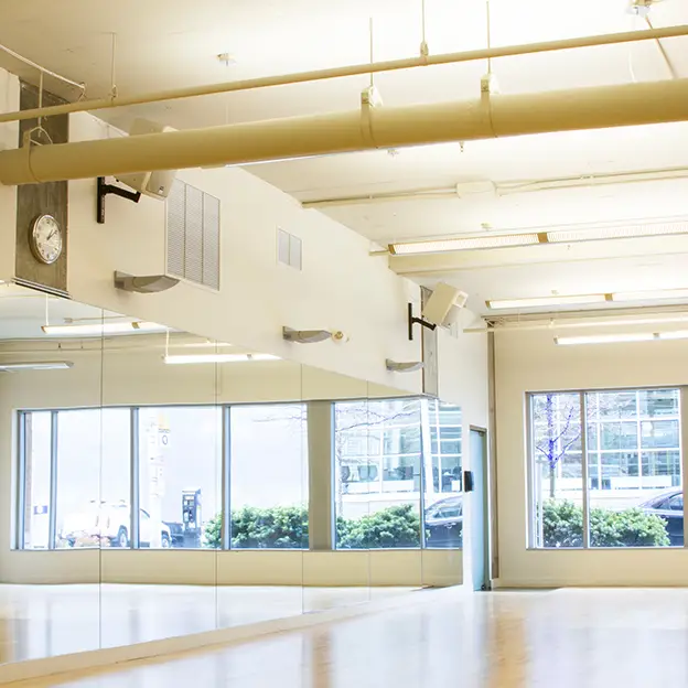 A large room with a mirror on the wall and a clock on the ceiling.