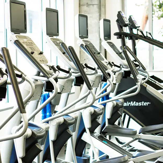 A row of exercise machines with a person standing in front of them.
