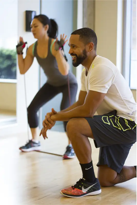 A man in a white shirt and black shorts is kneeling down.