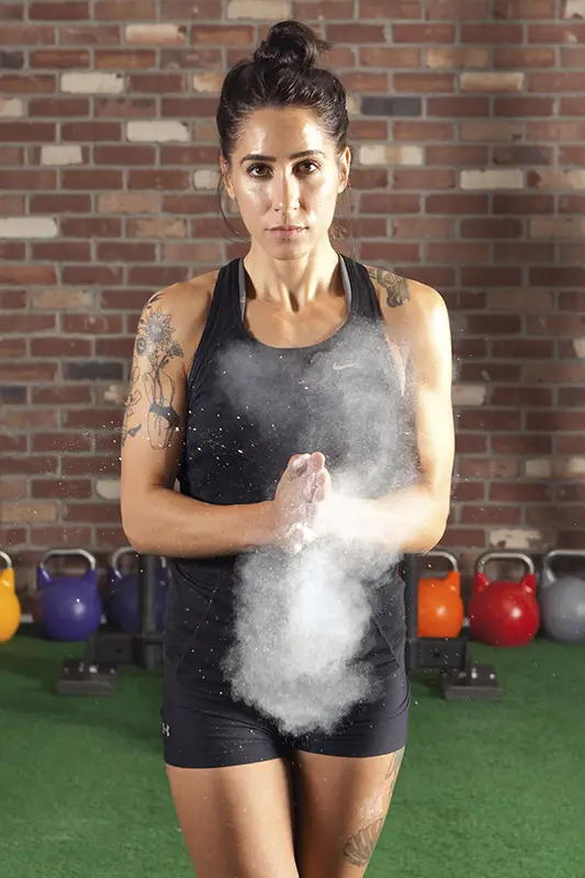 A woman with a tattoo and a black shirt is standing in front of a pile of powder.