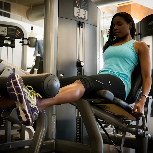 A woman is sitting on a machine in a gym.